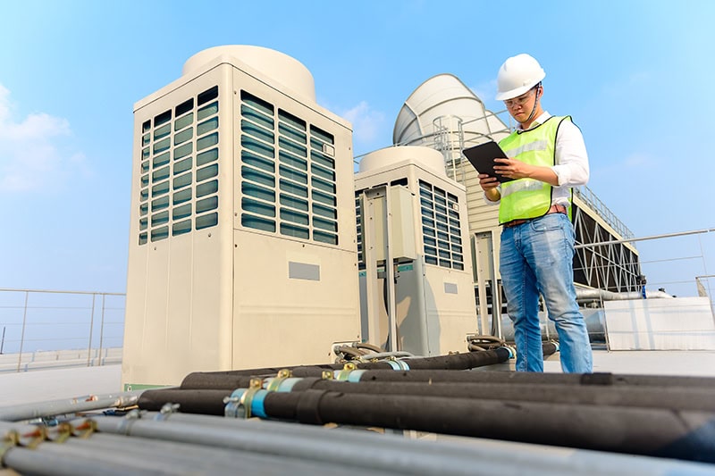 What Are the Benefits of Commercial HVAC Maintenance? A handyman inspecting equipment.