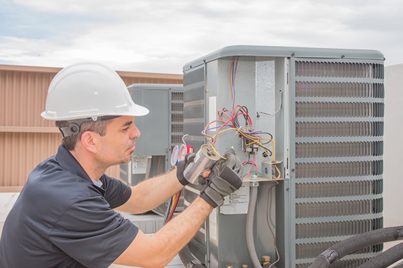 HVAC System Problems That Affect Employee Productivity and Health. Photo of a technician performing maintenance on a commercial HVAC unit installed on a rooftop.