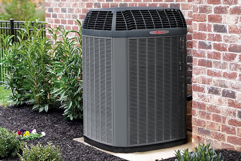 Spring AC Maintenance Tips. Photo of an HVAC until installed outside of a brick home or building.